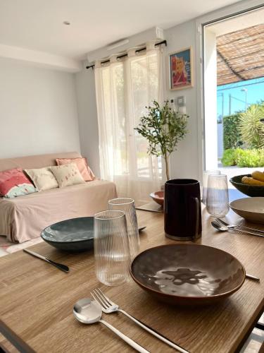 - une table à manger avec des assiettes et des ustensiles dans l'établissement Joli appartement privé jardin à 10min des plages, à Agde
