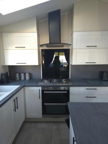 a kitchen with white cabinets and a stove top oven at Exclusive Gold 3 Bed Luxury Caravan in Port Seton