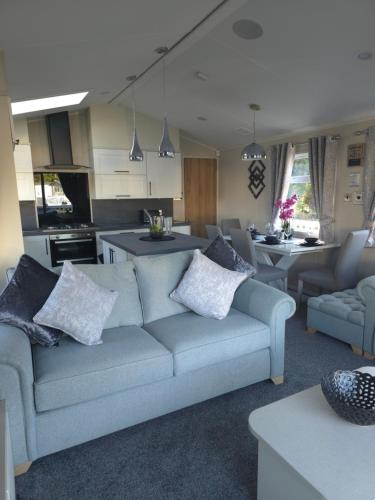 a living room with a couch and a kitchen at Exclusive Gold 3 Bed Luxury Caravan in Port Seton