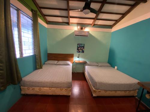 two beds in a room with blue walls at Lote 44 Guesthouse in El Zonte
