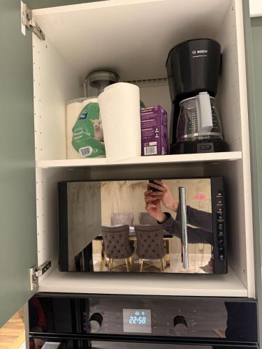 a microwave in a cabinet with a person inside at Apartment close to the city center in Sandefjord