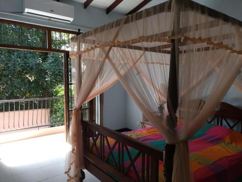 a bedroom with a canopy bed and a large window at A tropical paradise; stunning house, pool, garden in Wattala