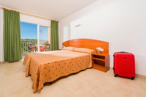 1 dormitorio con 1 cama y 1 maleta roja en Apartaments Condado, en Lloret de Mar