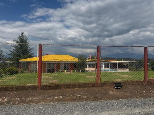 una recinzione di fronte a un edificio con tetto giallo di Cabaña en medio de la naturaleza en el norte de Popayán a Popayan