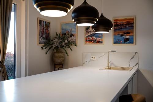 a kitchen with a white counter and two pendant lights at Sea Whisper apartment Zadar in Zadar