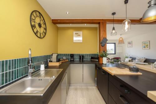 a kitchen with a sink and a clock on the wall at La Marine, maison en plein cœur de Wimereux in Wimereux