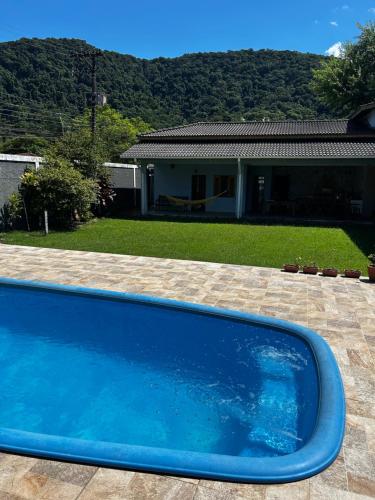 a blue swimming pool in front of a house at Morada das orquideas Quarto 6 in São Sebastião