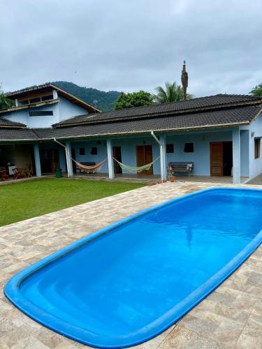 a blue swimming pool in front of a house at Morada das orquideas Quarto 6 in São Sebastião