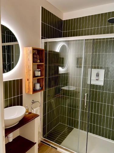 La salle de bains est pourvue de carrelage vert, d'un lavabo et d'une douche. dans l'établissement Le Mûrier, à Lourmarin