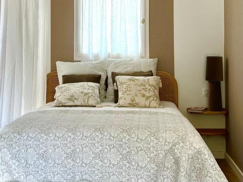 une chambre avec un lit blanc avec des oreillers et une fenêtre dans l'établissement Le Mûrier, à Lourmarin