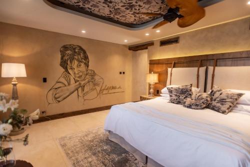 a bedroom with a large bed with a painting on the wall at La Maria Hotel Boutique in Chacras de Coria