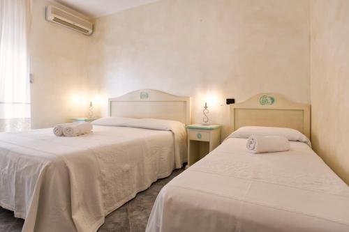 two beds in a room with white sheets and towels at Morpheo Rooms in Alghero
