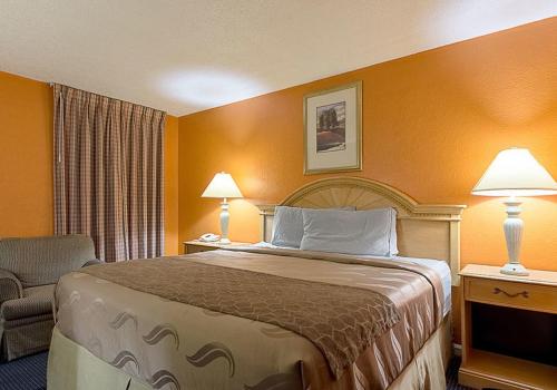 a hotel room with a bed and a chair and lamps at Highway Inn in Paris