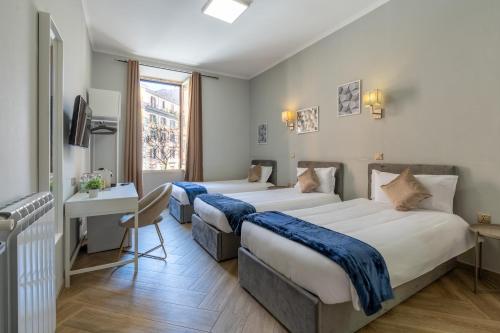 a hotel room with two beds and a desk at Portafortuna GUESTHOUSE - close to COLOSSEUM in Rome