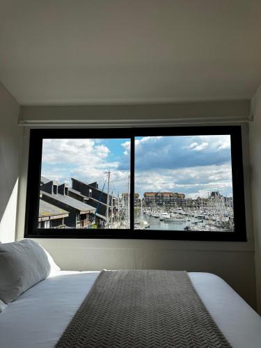 - une chambre avec une grande fenêtre offrant une vue sur le port dans l'établissement Bel appartement à Deauville - vue mer et port, à Deauville