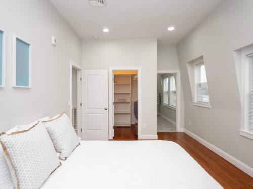 a white bedroom with a bed and a closet at Jennifers Penthouse Panoramic City View Apartment with Deck in Providence
