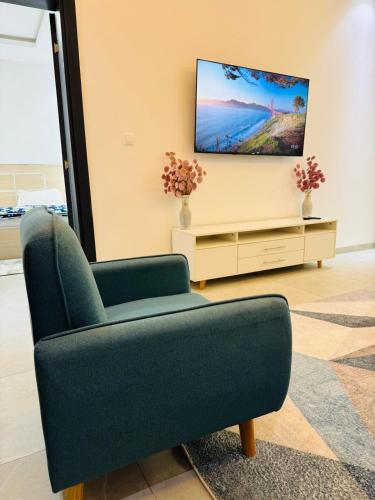 a living room with a green chair and a flat screen tv at Studio au virage in Dakar