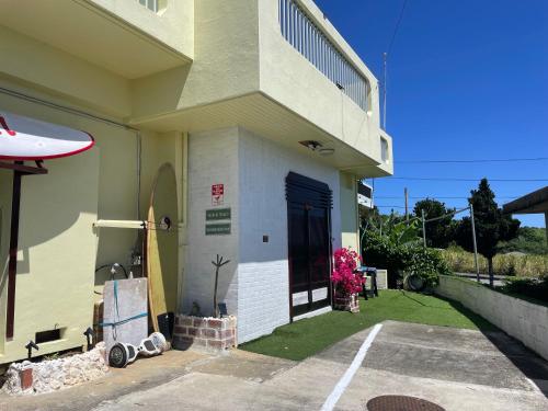 a building with a blue door and a parking lot at 宮古島ゲストハウス　マウイ in Arazato