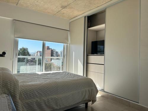 een slaapkamer met een bed en een groot raam bij BELGRANO SUITES in Salta