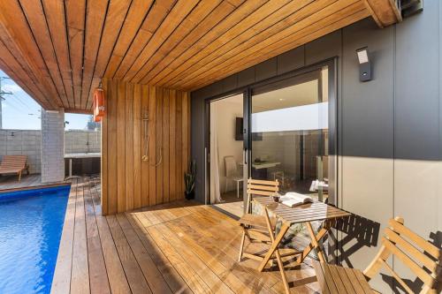 a patio with a table and chairs next to a pool at Luxury Papamoa Beach House with Pool and Spa Pet Friendly in Papamoa