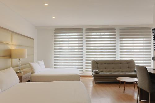 a hotel room with a couch and a chair at Hotel Hill House Usaquén in Bogotá