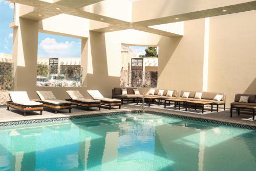 a pool in a hotel lobby with chairs and tables at Hotel Hacienda Aguacaliente in Tijuana