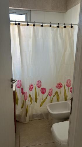 een badkamer met een toilet en een douchegordijn met roze bloemen bij BELGRANO SUITES in Salta