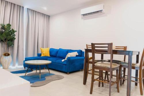 a living room with a blue couch and a table at Zimansky Apartments in Accra