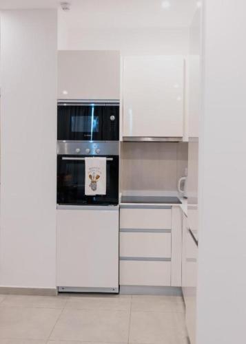 a kitchen with a white refrigerator and white cabinets at Zimansky Apartments in Accra