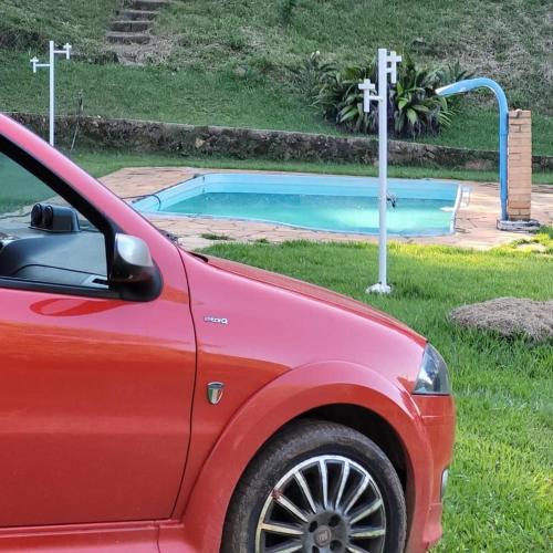 a red car parked in front of a swimming pool at Sitio Bárbara in Brumadinho
