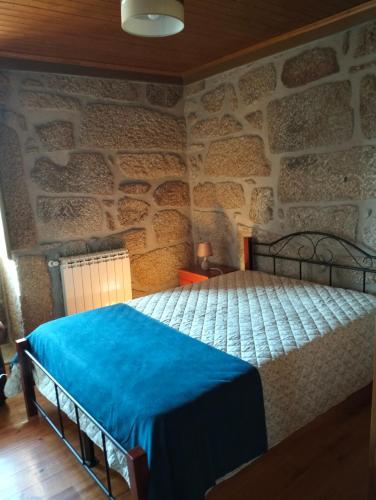 a bedroom with a bed in a stone wall at Serra da Estrela - Casa Castro in Gouveia