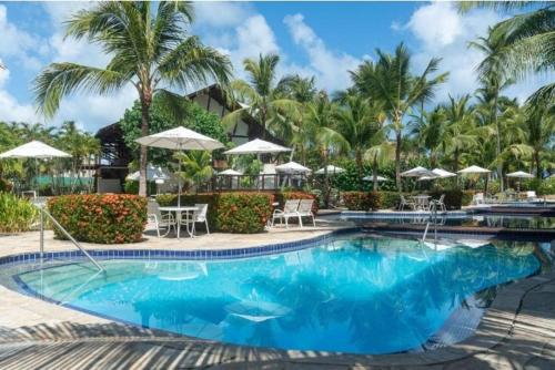 a pool at a resort with palm trees and umbrellas at Nannai Residence - Muro Alto - Porto de Galinhas in Porto De Galinhas