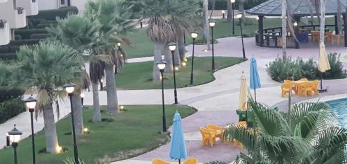 an aerial view of a resort with a pool and palm trees at شالية 3 غرف - بقرية نيس 4 - الساحل الشمالي in Dawwār Abū Duray‘ah ‘Abd al Karīm