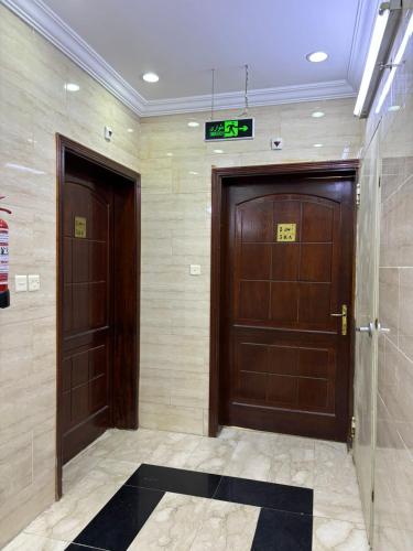 two brown doors in a hallway with a sign on it at سبل الذهبية للشقق المخدومة in An Naqāʼ