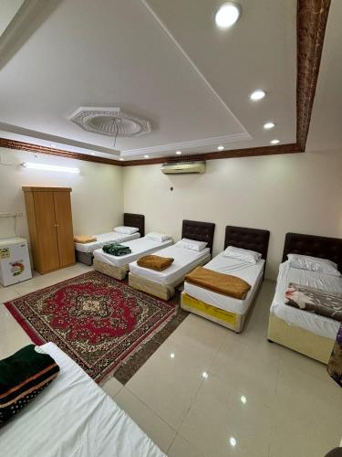 a room with four beds and a rug at سبل الذهبية للشقق المخدومة in An Naqāʼ