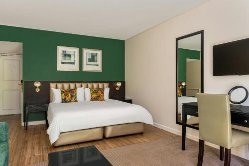 サマーセット・ウェストにあるLord Charles Hotel, Somerset West, a Tribute Portfolio Hotelのベッドと机と鏡のある寝室