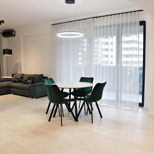 a dining room with a table and green chairs at Via Vida I 2 Bedroom Apartments on Pipera Blvd in Voluntari