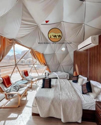 a bedroom in a tent with a bed and chairs at RUM BUBBLES VIEW lUXURY CAMP in Wadi Rum