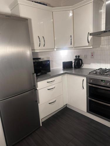 a kitchen with white cabinets and a stainless steel refrigerator at City LUX Apartment in London