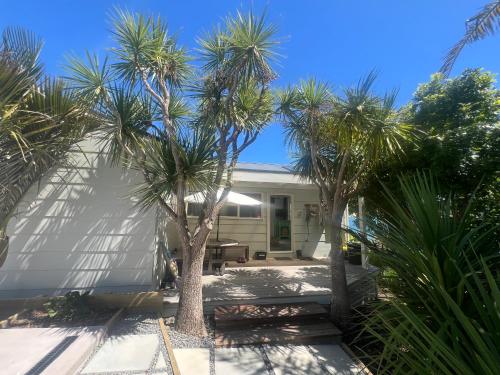 a house with palm trees in front of it at 180 Degrees Opononi in Opononi