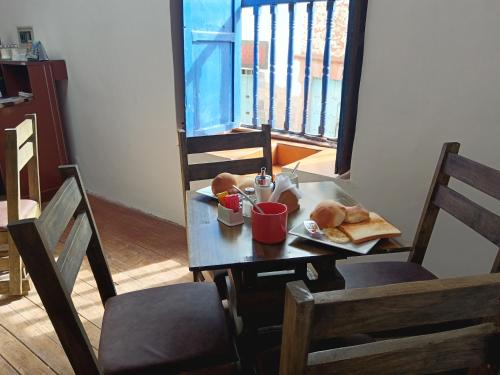 a table with a plate of food and bread on it at Auquis Hostel in Cusco