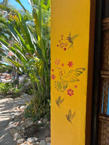 a yellow post with flowers and a bird painted on it at OCEAN OASIS HOTEL - adult only, four casitas boutique resort in Playa Agua Blanca