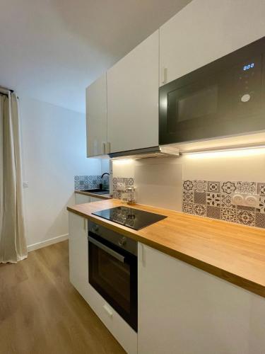 une cuisine avec des armoires blanches et un four à plaques de cuisson dans l'établissement Studio Cosy Vannes Centre, à Vannes