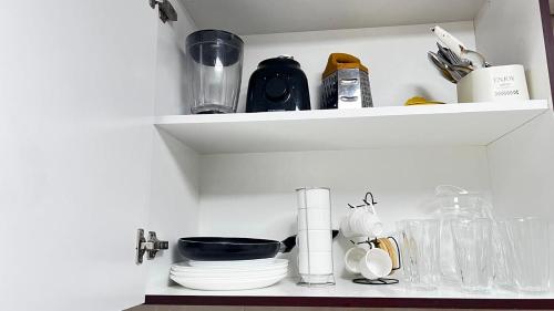 a shelf with dishes and other kitchen items on it at Rest House Hostel in Abu Dhabi