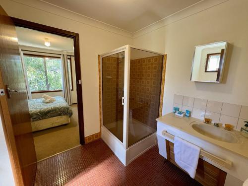 a bathroom with a shower and a sink and a bed at Dunsborough Delight in Dunsborough