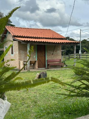 a small brick house with a bench in a yard at Chalés e Camping Taquaral in São Thomé das Letras