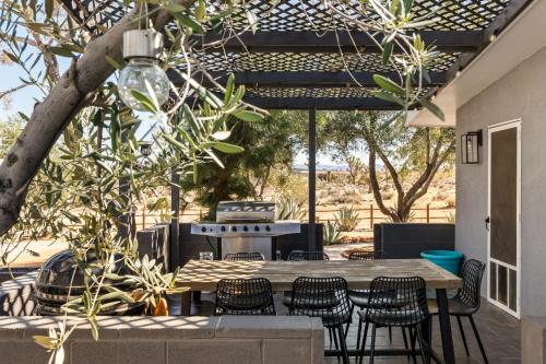 a patio with a table and chairs and a grill at Sunset Grove By The Cohost Company in Yucca Valley