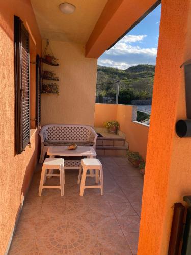 a patio with a bench and two stools on a balcony at Family friendly house with a swimming pool Mijaca, Zagora - 21267 in Vrgorac