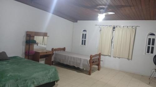 une chambre avec un lit et un bureau dans une pièce dans l'établissement Casa Glória macaé, à Macaé