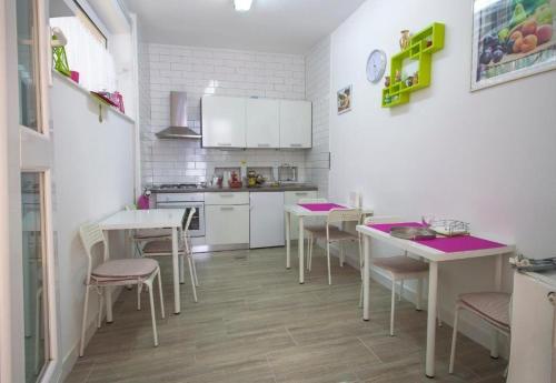 uma cozinha com balcões brancos, mesas e cadeiras em Rooms with WiFi Zagreb - 24079 em Zagreb